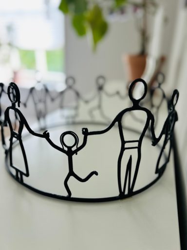 Svart smidesjärn figurer som håller varandra i handen.